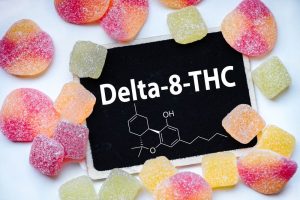 the chemical delta 8 thc on a chalk board surrounded with gummy edibles