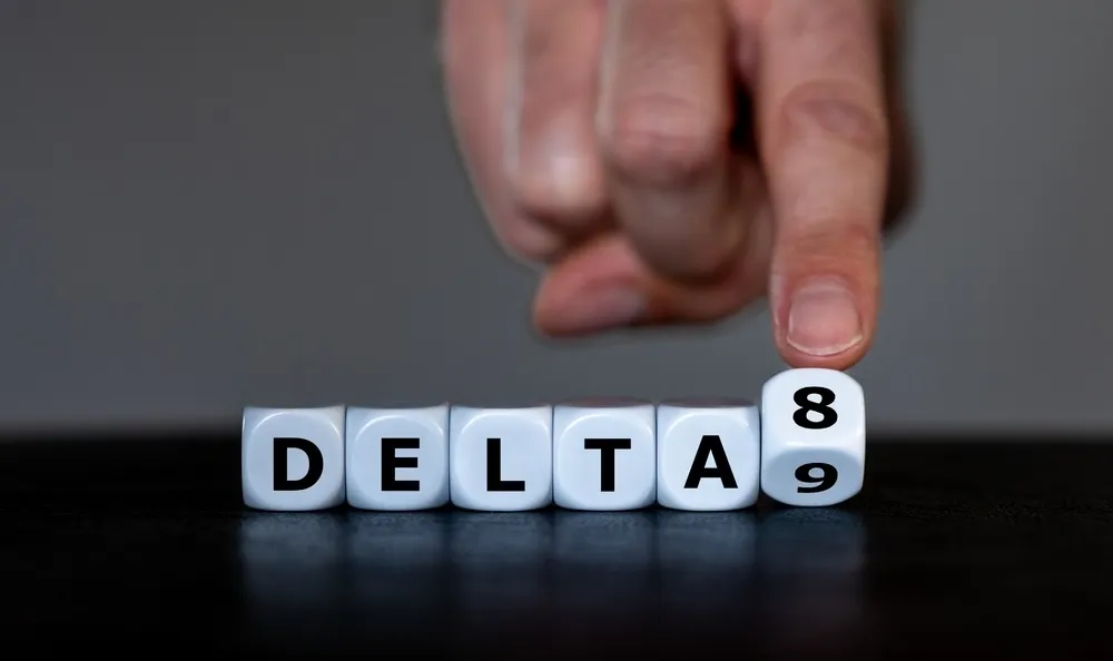 die with letters spelling out delta8 with a finger flipping 1 dice from the number 8 to 9